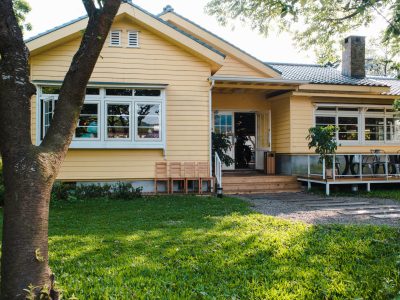 A charming yellow house with wooden windows and green grassy garden